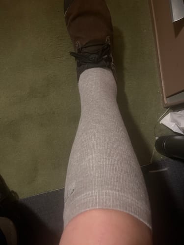 Reviewer wearing a light gray, ribbed Premium Bamboo Compression Sock on their lower leg.