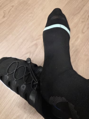 Customer's foot wearing a black Premium Bamboo Compression Sock with a light blue band at the top.