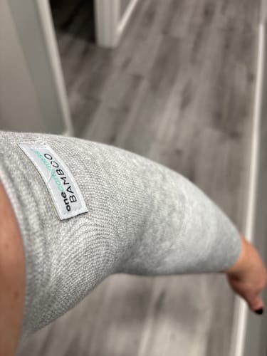 Customer wearing the light grey Premium Bamboo Compression Sock over their knee, showing the knit texture.