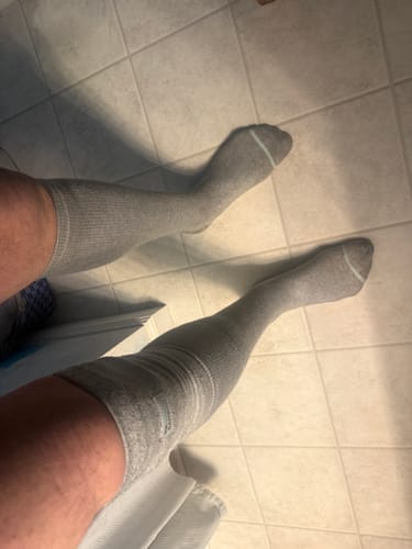 Reviewer's legs wearing the knee-high, grey Premium Bamboo Compression Socks on a tiled floor.
