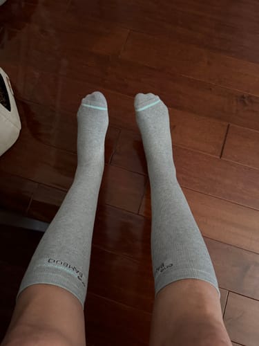 Customer showing the fit of the grey Premium Bamboo Compression Socks on their lower legs against a wood floor.