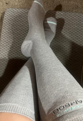 A reviewer resting their legs while wearing the light grey, ribbed Premium Bamboo Compression Socks.