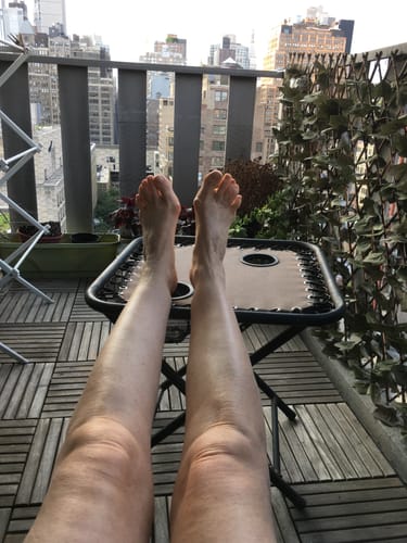 Customer's legs resting on a patio table while wearing bamboo compression socks on a balcony overlooking a city.