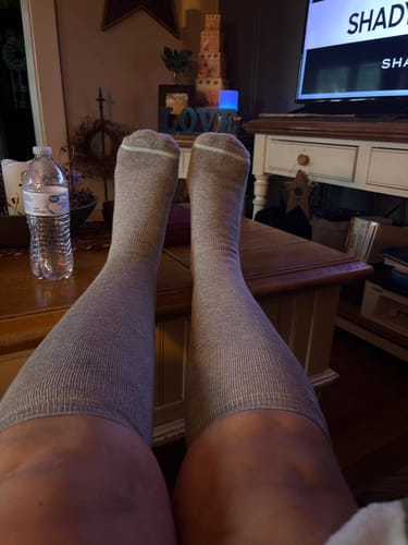 Customer relaxing with their feet up while wearing the grey Premium Bamboo Compression Socks in a living room.