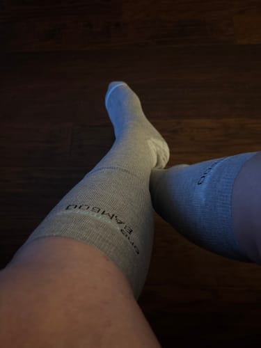 Reviewer wearing the grey Premium Bamboo Compression Socks with their legs crossed.