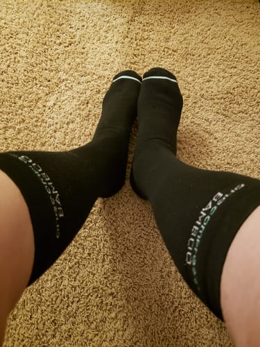 Customer's black Premium Bamboo Compression Socks worn on both legs while standing on a beige carpet.