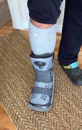 Customer wearing a light grey Premium Bamboo Compression Sock with a medical walking boot for foot recovery.